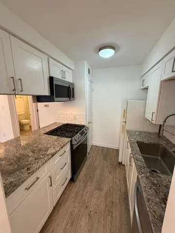 a kitchen with granite countertop a sink stove and refrigerator