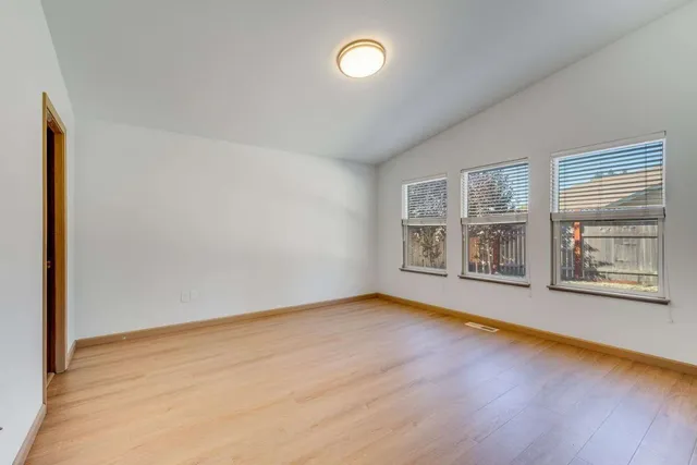 a view of an empty room with a window and wooden floor