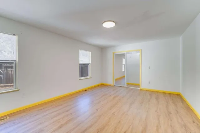 a view of an empty room with wooden floor and a window