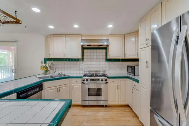 a kitchen with stainless steel appliances granite countertop a stove a refrigerator and a sink