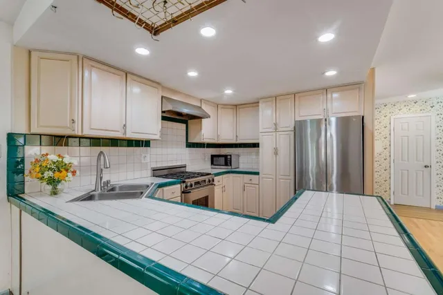 a kitchen with stainless steel appliances granite countertop a sink refrigerator and cabinets