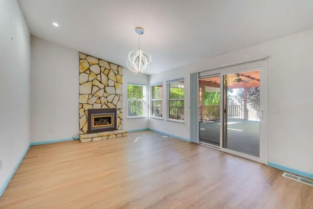an empty room with windows a fireplace and wooden floor