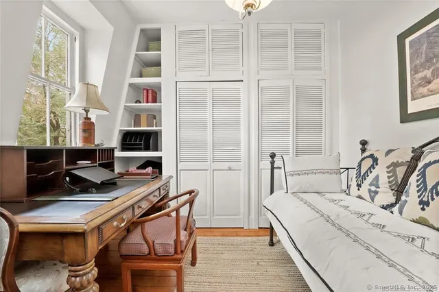 a bedroom with a bed a computer on desk and a windows