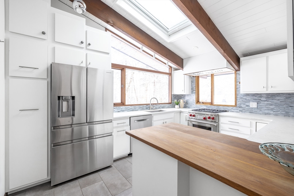 134 Rangeley Road Brookline, MA 02467 - Photo 6 of 27 a kitchen with stainless steel appliances granite countertop a refrigerator a sink dishwasher a stove and white countertops with wooden floor