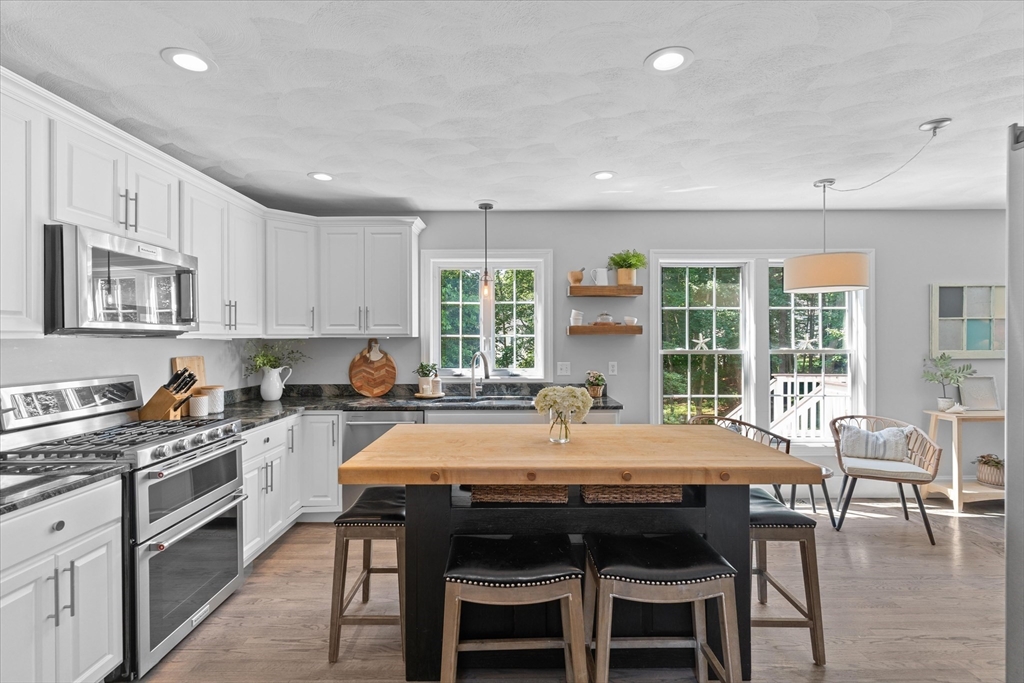 69 Curzon Mill Road Newburyport, MA 01950 - Photo 8 of 40 a kitchen with granite countertop a stove a table and chairs in it