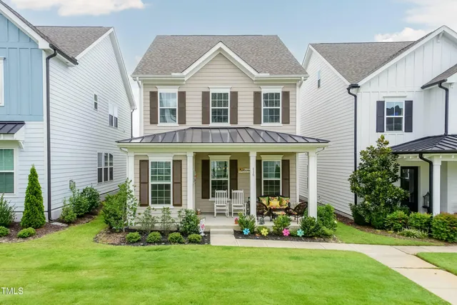 a front view of a house with a yard and potted plants