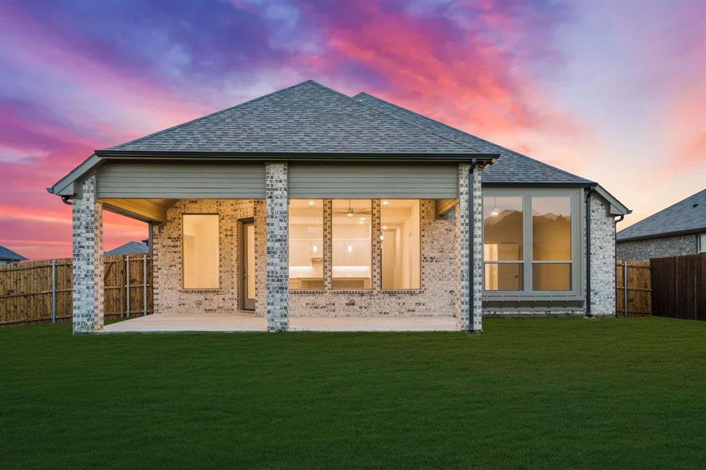 139 Lakeview Circle Pilot Point, TX 76258 - Photo 13 of 19 Back of house at dusk featuring a yard, a fenced backyard, brick siding, and roof with shingles