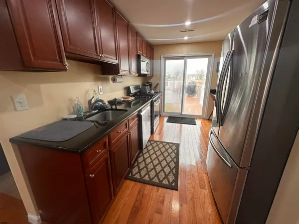 a kitchen with stainless steel appliances granite countertop a refrigerator a sink a stove and a refrigerator