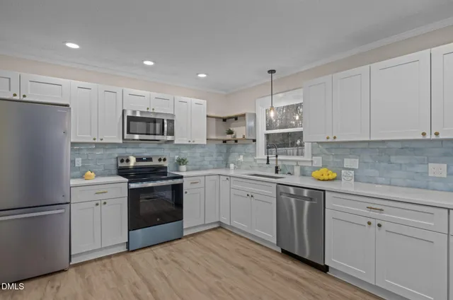a kitchen with a sink a stove a refrigerator and white cabinets