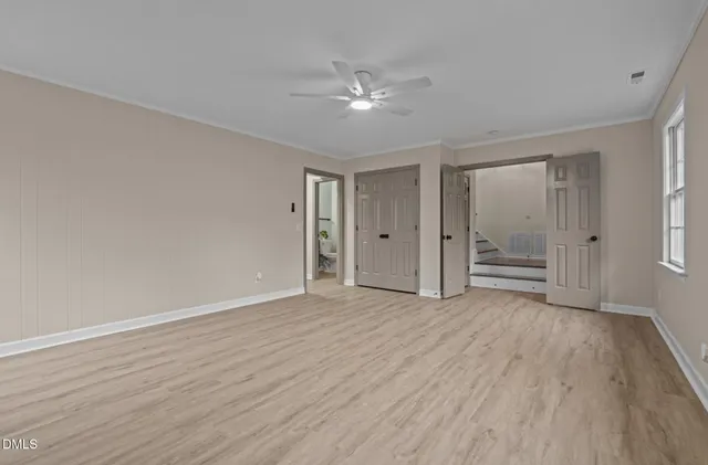 an empty room with wooden floor and windows