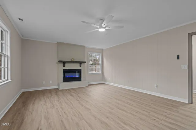 a view of an empty room with wooden floor fireplace and a window