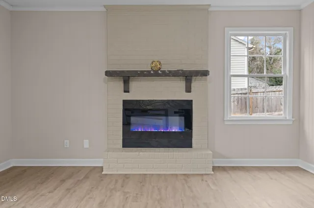 a view of an empty room with wooden floor and a fireplace