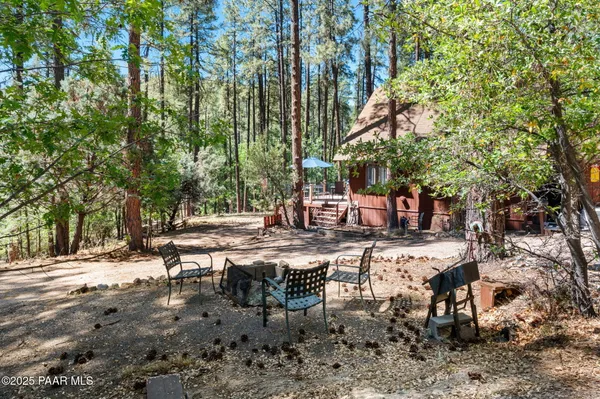 a view of a house with large trees and sitting area