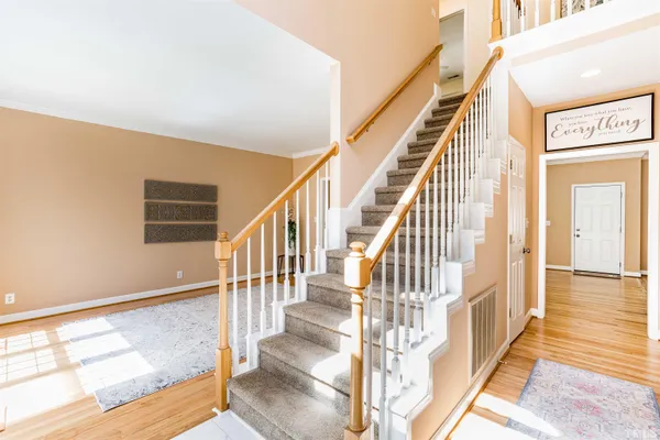 a view of staircase with lots of frames on wall and wooden floor
