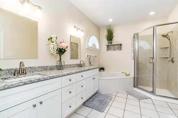 a spacious bathroom with a granite countertop sink mirror and a bathtub