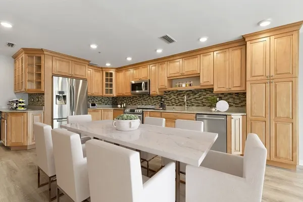 a kitchen with stainless steel appliances granite countertop a refrigerator a stove and white cabinets with wooden floors