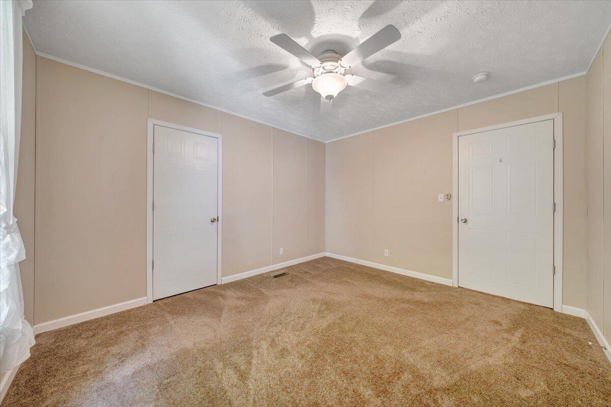 460 White Oak Road Boones Mill, VA 24065 - Photo 21 of 45 an empty room with a chandelier fan and windows