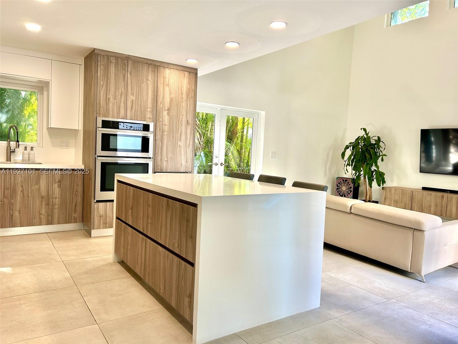 4445 Red Road Coral Gables, FL 33146 - Photo 13 of 41 a kitchen with kitchen island white cabinets and stainless steel appliances