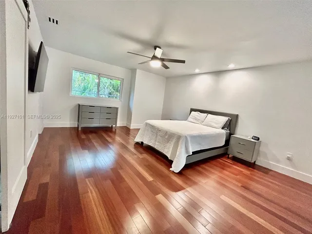 a bedroom with a bed and a flat tv screen on dresser