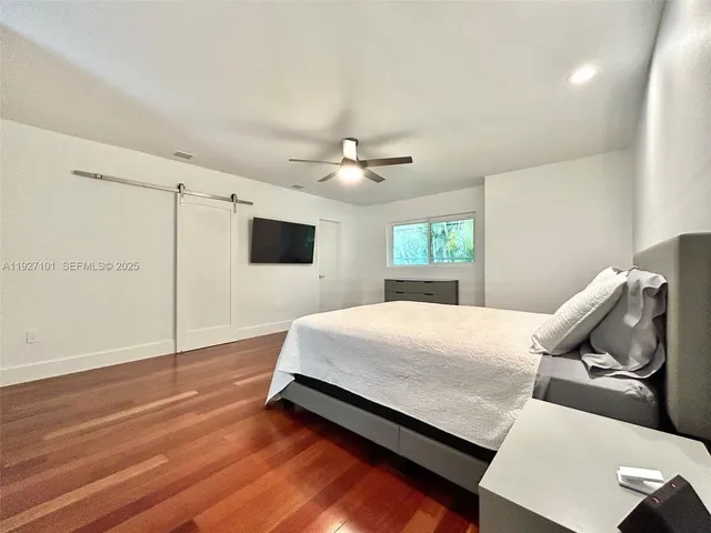a spacious bedroom with a bed and a flat screen tv