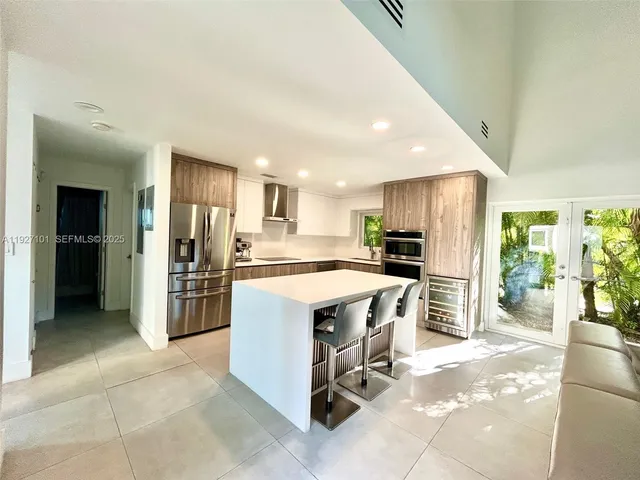 a kitchen with stainless steel appliances kitchen island granite countertop a refrigerator and a stove top oven