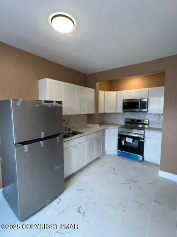 a kitchen with stainless steel appliances a refrigerator sink and stove