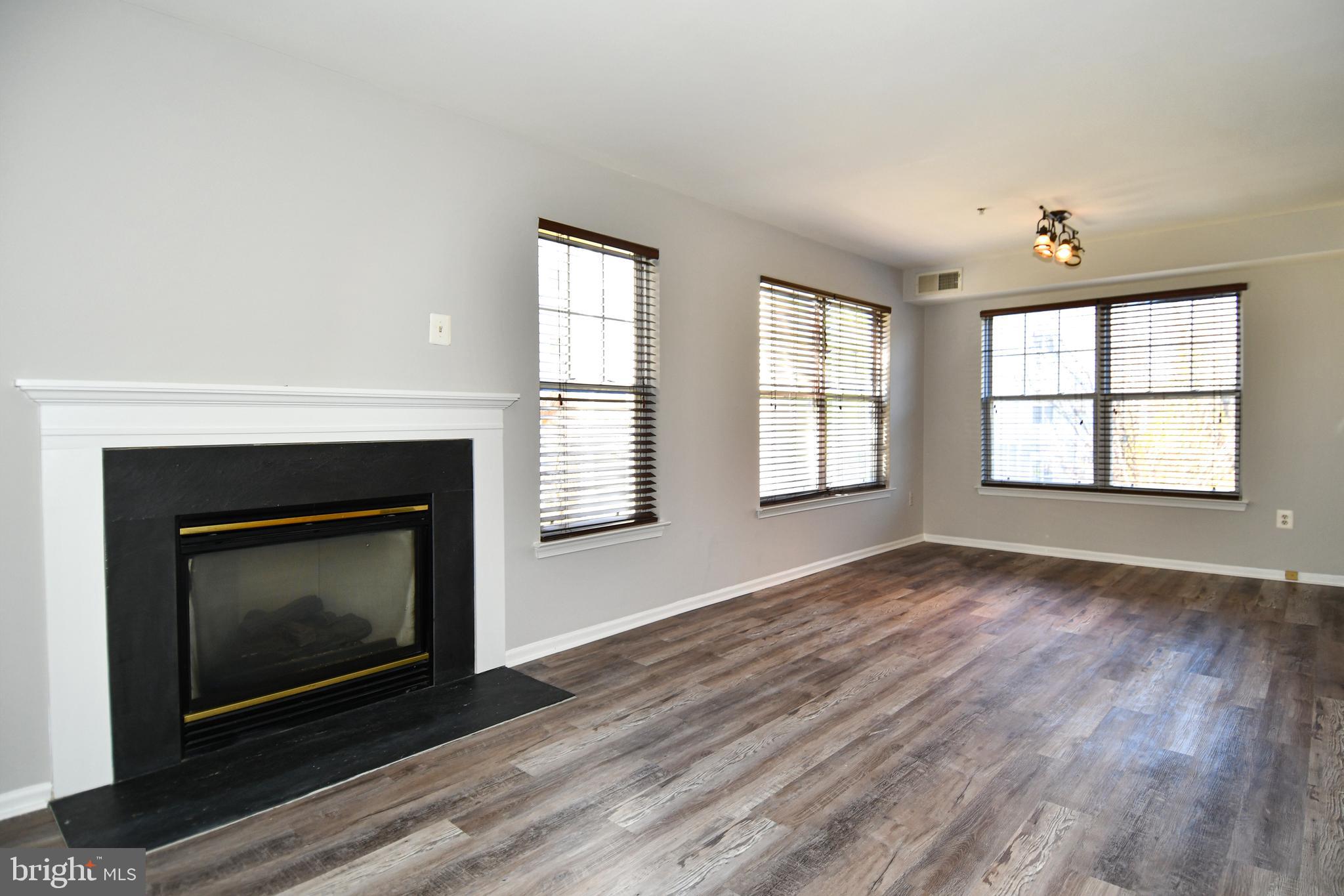 14100 Farnsworth Lane, Unit 2202 Upper Marlboro, MD 20772 - Photo 17 of 38 an empty room with wooden floor fireplace and windows