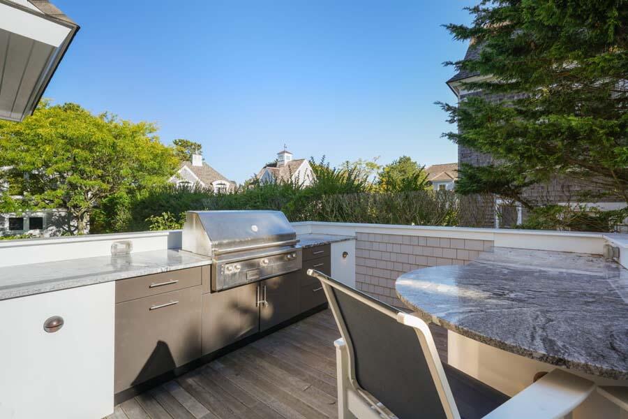 27 Ocean Bluff Drive Mashpee, MA 02649 - Photo 18 of 55 a view of a patio with table and chairs a barbeque with wooden fence and plants