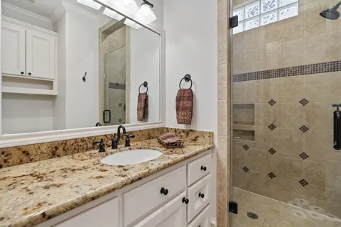 a bathroom with a granite countertop sink a mirror a shower and a bathtub