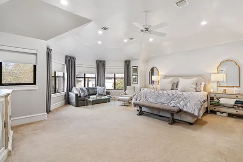 a spacious bedroom with a bed a couch and a chandelier