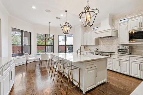 a kitchen with stainless steel appliances granite countertop a stove a sink dishwasher a dining table and chairs with wooden floor