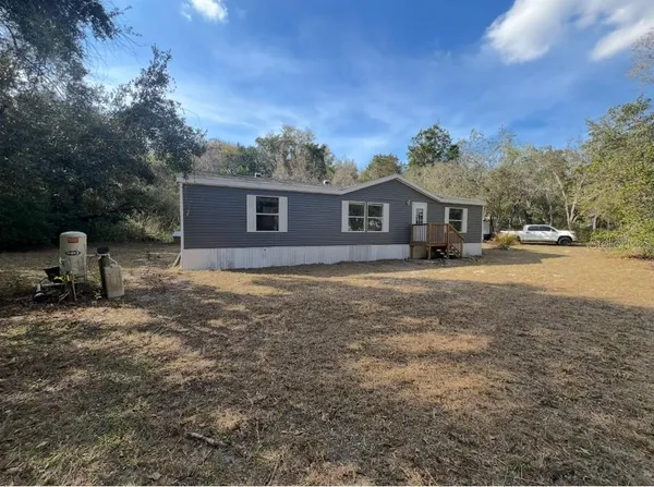 a front view of house with yard and trees in the background
