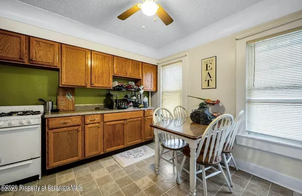 a kitchen with stainless steel appliances granite countertop a sink a stove a dining table and chairs with wooden floor