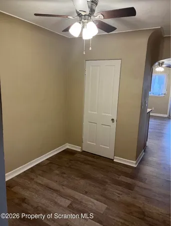 an empty room with wooden floor closet and windows