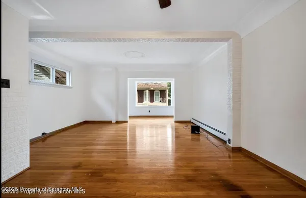 a view of an empty room with wooden floor and a window