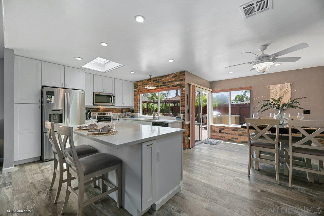 a kitchen with stainless steel appliances kitchen island granite countertop a table chairs cabinets and wooden floor