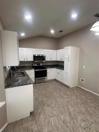 a large kitchen with stainless steel appliances granite countertop a stove a sink and a refrigerator