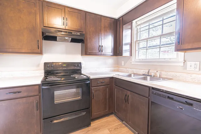 a kitchen with granite countertop stainless steel appliances a sink stove and cabinets