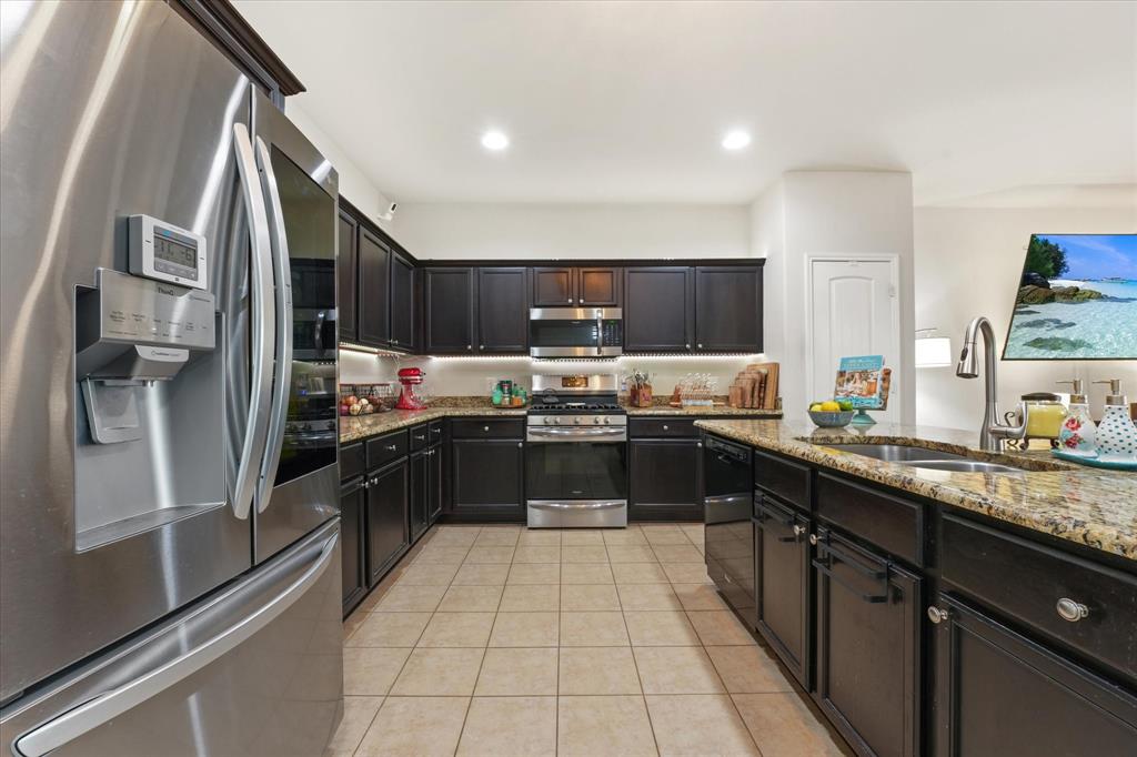 3801 Surf Street Denton, TX 76208 - Photo 6 of 29 Kitchen with stainless steel appliances, light stone counters, recessed lighting, and light tile patterned flooring