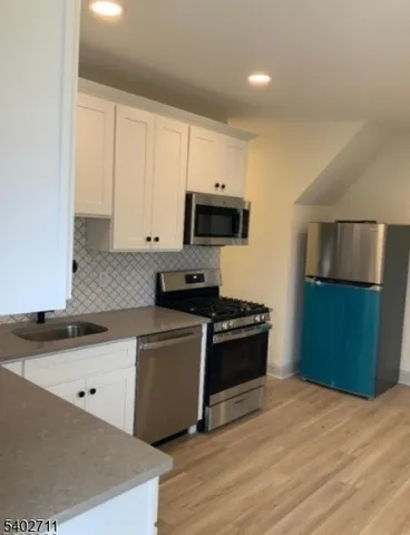 a kitchen with granite countertop a refrigerator stove and sink