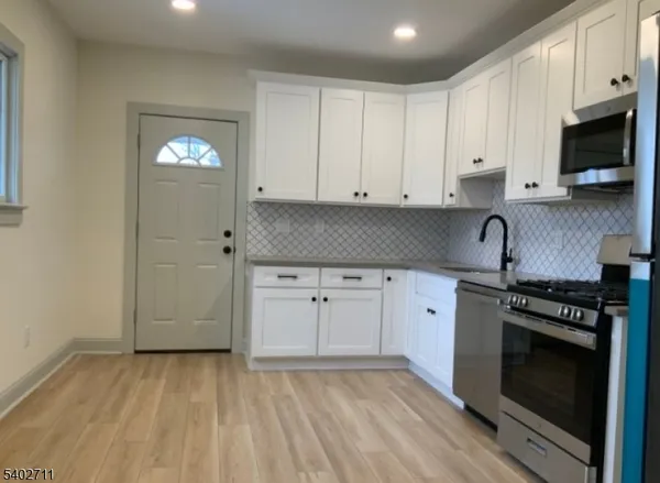 a kitchen with granite countertop white cabinets and stainless steel appliances