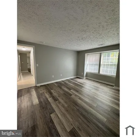 a view of an empty room and window and wooden floor