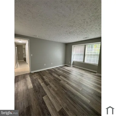 a view of an empty room and window and wooden floor