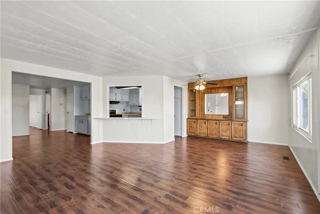 a view of an empty room with window and wooden floor