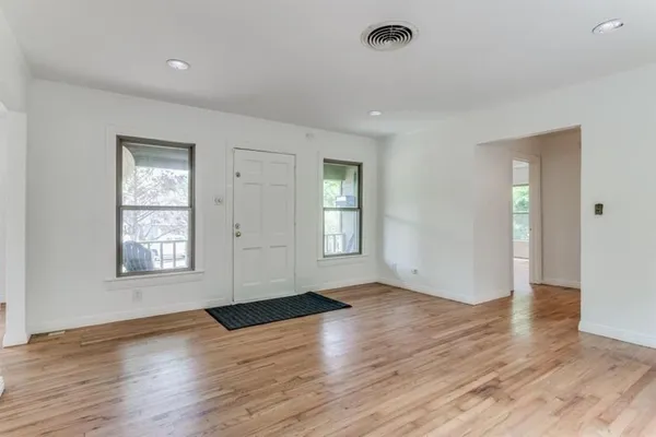an empty room with wooden floor and windows