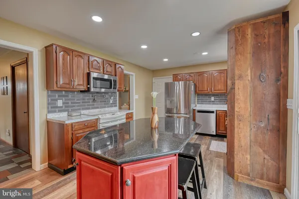 a kitchen with stainless steel appliances granite countertop a refrigerator a stove and a sink with wooden cabinets