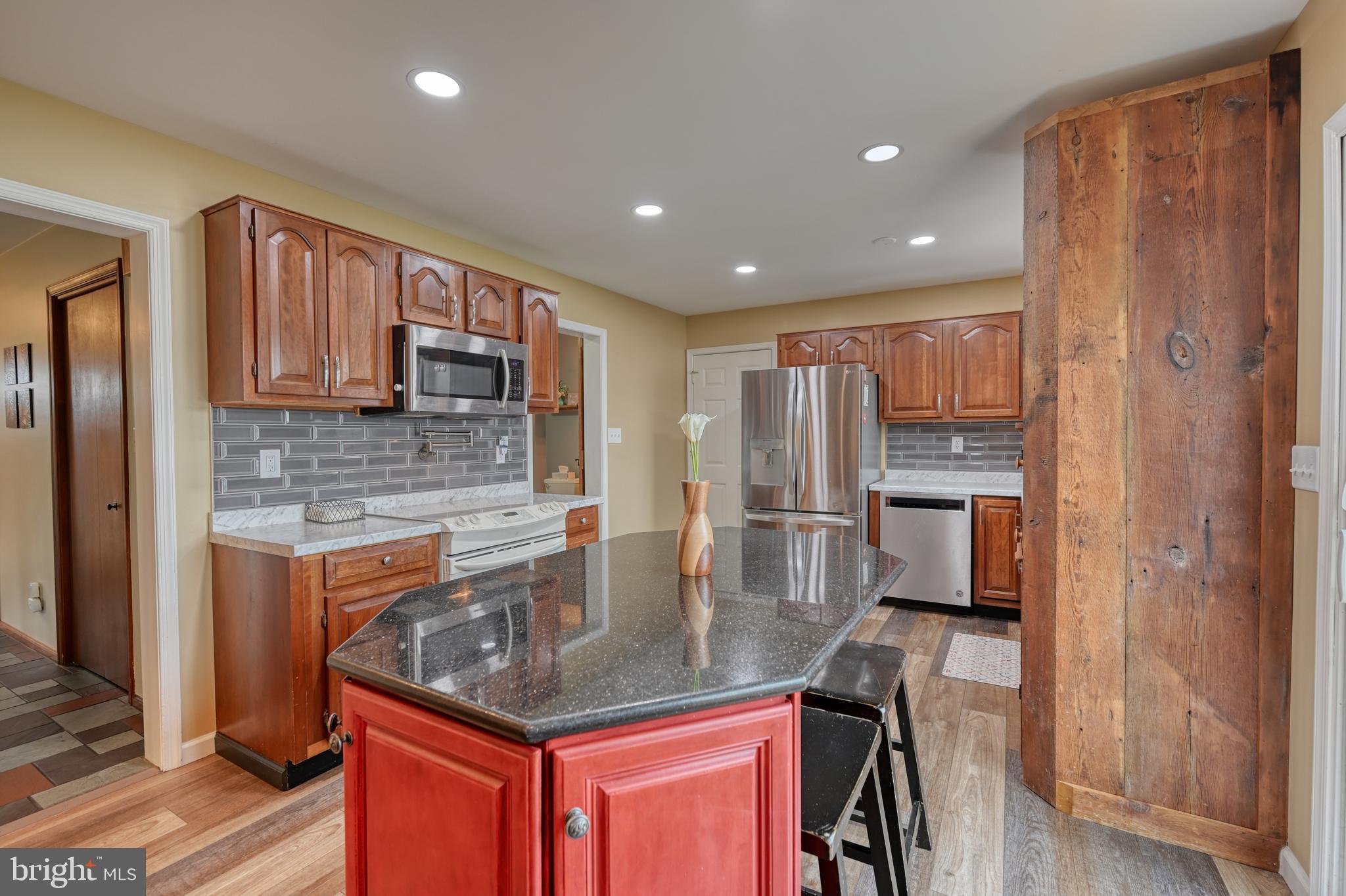 3320 Rothsville Road Akron, PA 17501 - Photo 11 of 41 a kitchen with stainless steel appliances granite countertop a refrigerator a stove and a sink with wooden cabinets