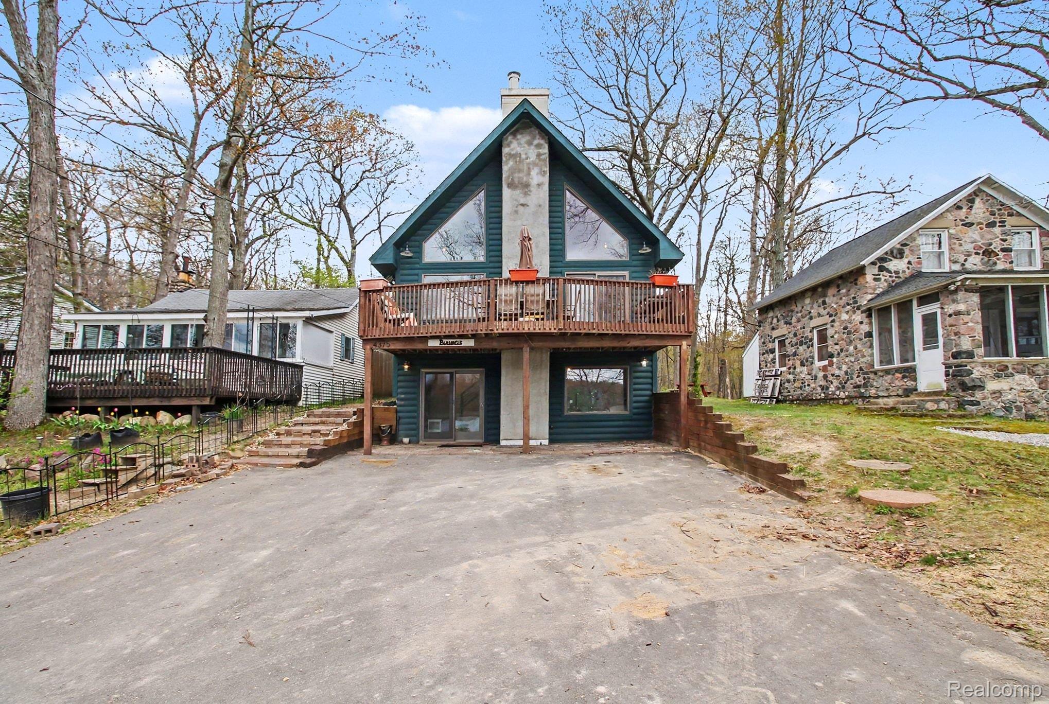 4375 Skinner Lake Road Lapeer, MI 48446 - Photo 2 of 30 Rustic home featuring a deck, asphalt driveway, and a chimney
