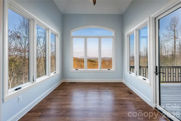 a view of an empty room with a window and wooden floor