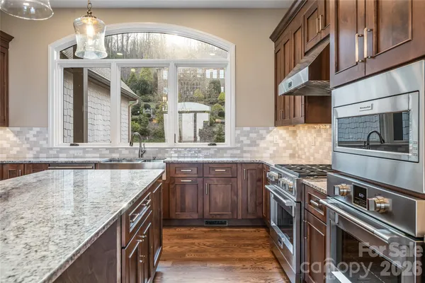 a kitchen with stainless steel appliances granite countertop a sink stove and cabinets